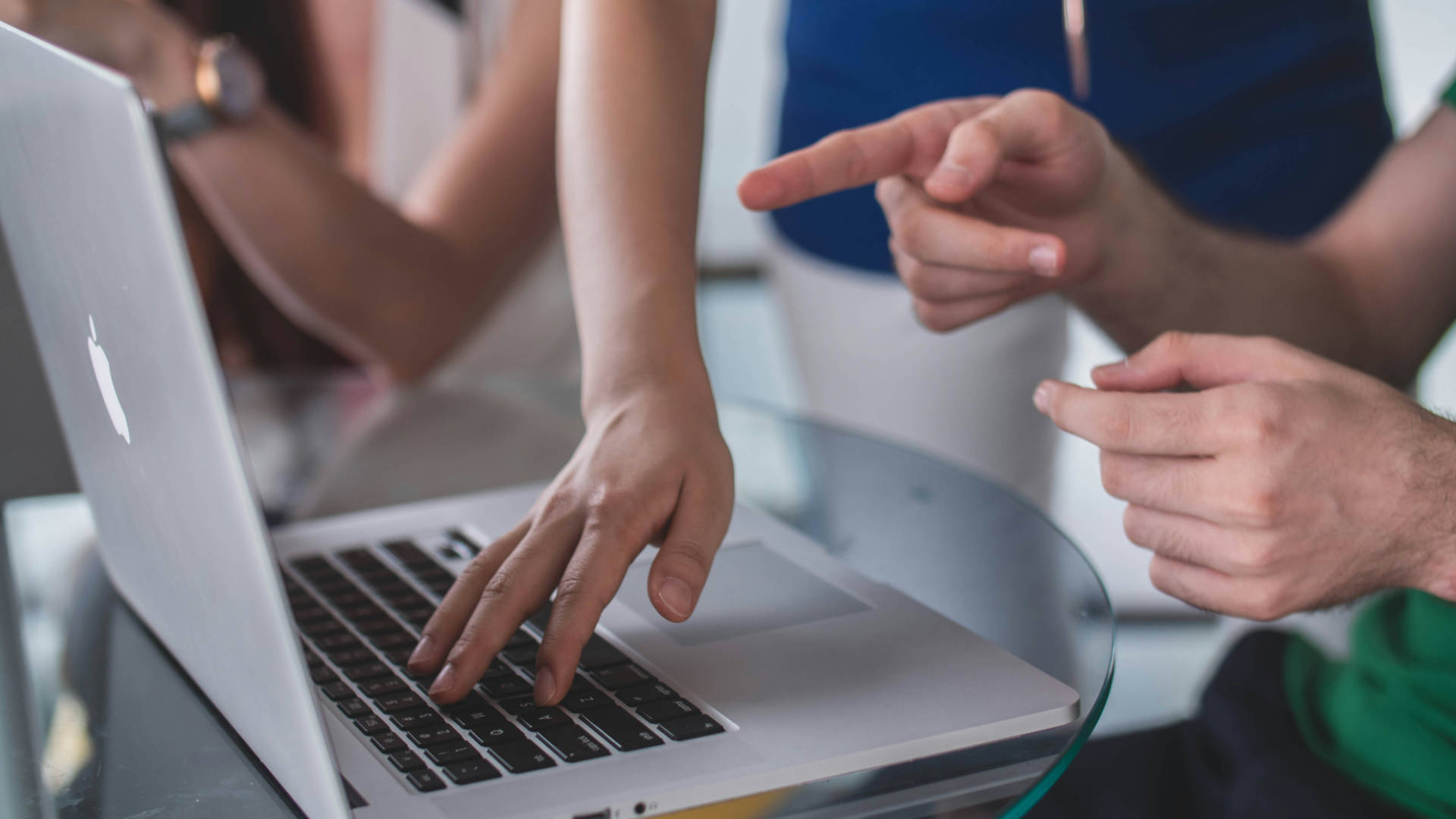 Two people using a laptop with one pointing at the screen