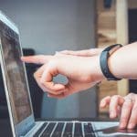 Two people pointing at a laptop screen