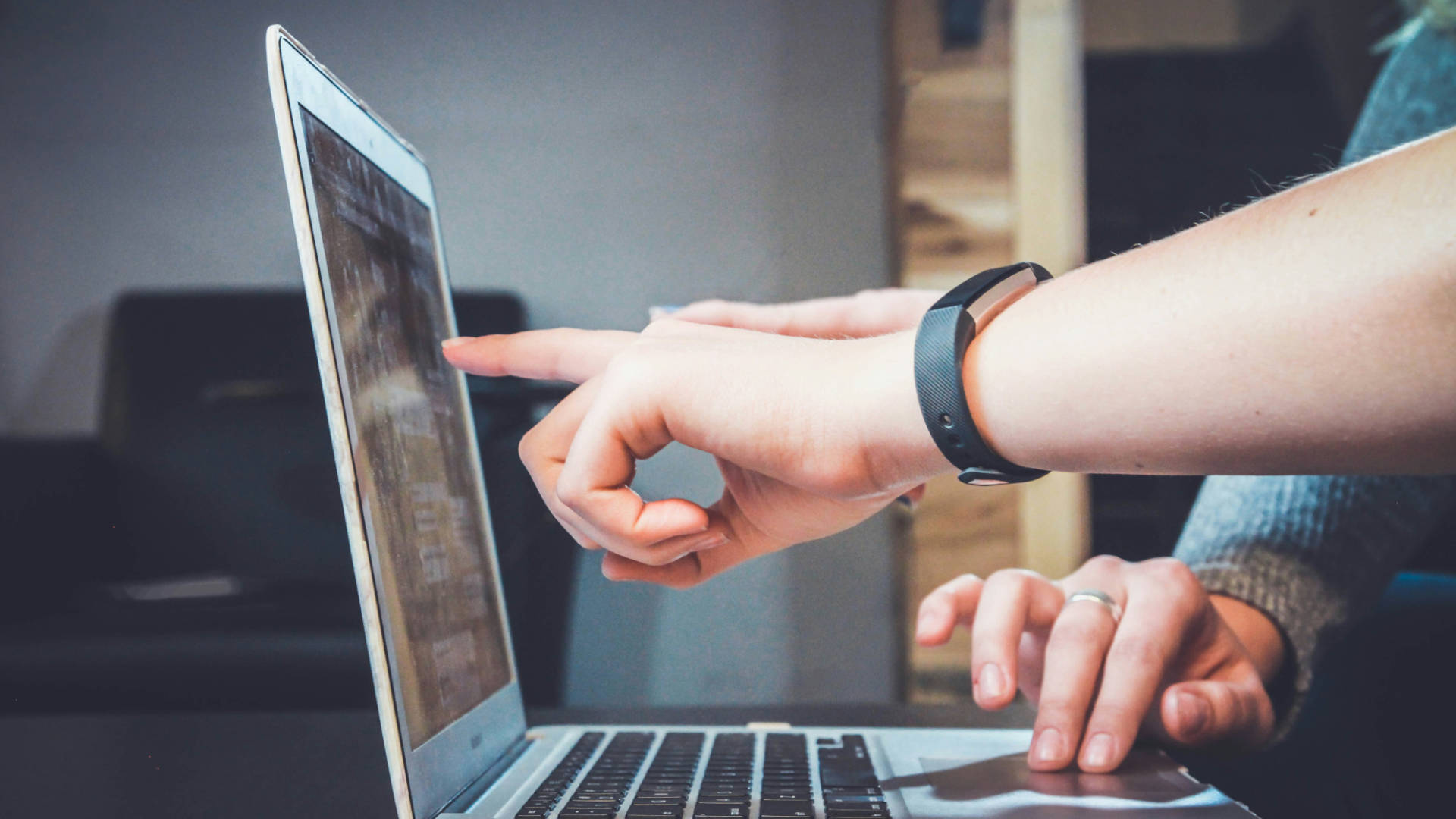 Two people pointing at a laptop screen