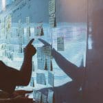 Someone pointing at a whiteboard covered with post it notes