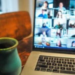 A cup of tea on a desk in front of a video conference screen