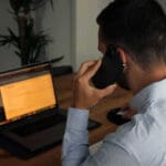 A person on a phone call as well as using their laptop