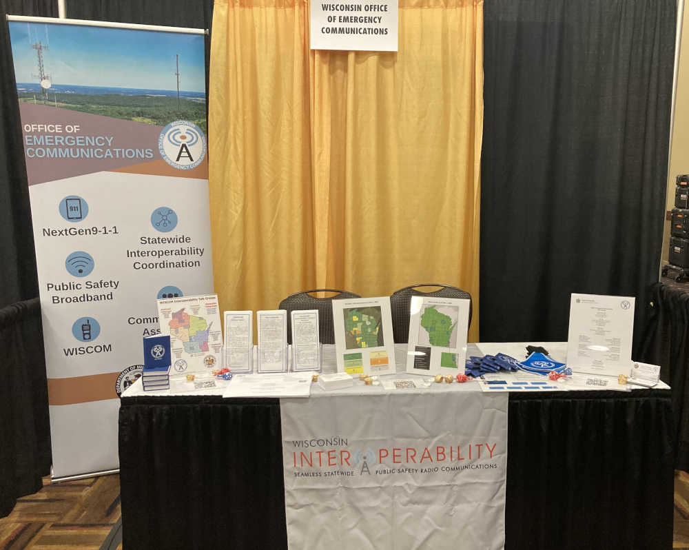 OEC event booth with brochures and giveaway items displayed on a table.